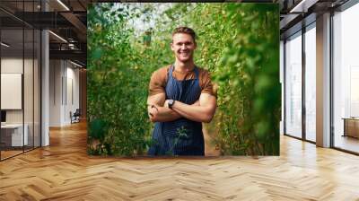 Im living on the green side of life. Portrait of a handsome young farmer posing with his arms folded in the fields at his farm. Wall mural