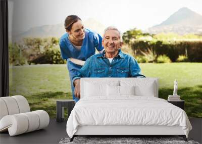 Is the fresh air helping. Cropped shot of a young female nurse outside with a senior patient in a wheelchair. Wall mural