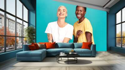 Life is beautiful with your bestie by your side. Studio shot of two happy young women posing together against a turquoise background. Wall mural