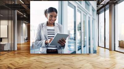 One young corporate intern worker browsing on wireless technology. Smiling businesswoman working on a tablet, reading email message online or checking company SEO website data in modern office. Wall mural