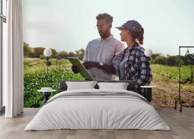 Our growth is phenomenal. Cropped shot of two young farmers looking at a tablet while working on their farm. Wall mural