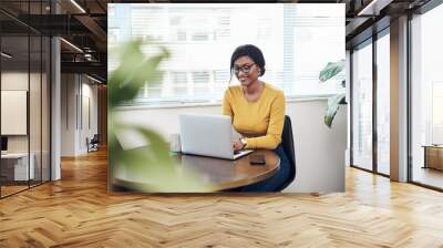 Preparing my next blog post. Shot of an attractive young woman sitting alone at home and using her laptop. Wall mural