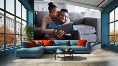 Sharing in a very special connection. Shot of a young couple using a digital tablet together while relaxing at home. Wall mural