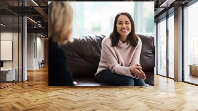 Therapy, happy women have a conversation on sofa and speaking or talking with a psychologist. Mental health or communication, support or consulting and people on couch have a discussion together Wall mural