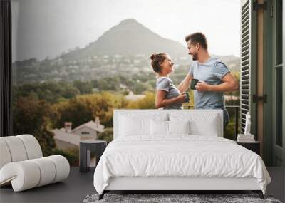 This is how we spend our weekends. Shot of an affectionate young couple drinking coffee while standing on their balcony at home in the morning. Wall mural