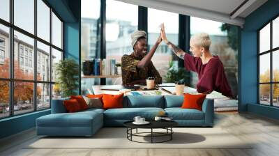 Yes We did it. Cropped shot of two attractive young businesswomen sitting in the office and giving each other a high five. Wall mural