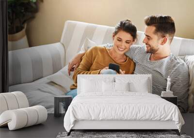 Sofa, couple and relax with smartphone for joke, conversation and bonding together with connection. Happy people, man and woman with cellphone for mobile app, social media and online meme at home Wall mural