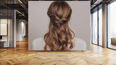 A back view of a twisted half-up hairstyle with loose waves, creating a romantic and feminine look. Wall mural