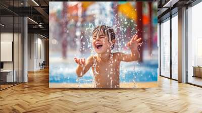 A child laughing and playing in a splash pad, with water jets spraying around and colorful structures in the background. Wall mural