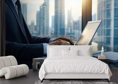 businessman typing on a laptop at a sleek office desk, with documents spread around and a city view in the background Wall mural