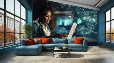 Cheerful young African American woman using laptop in blurry office with double exposure of futuristic network interface and planet hologram. Concept of internet and communication. Wall mural