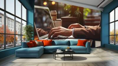 Cropped image of a young man working on his laptop in a coffee shop, rear view of business man hands busy using laptop at office desk, young male student typing on computer sitting at wooden table Wall mural