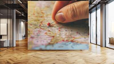 Female hand using a pin to mark a location on a map, highlighting travel planning and logistics Wall mural