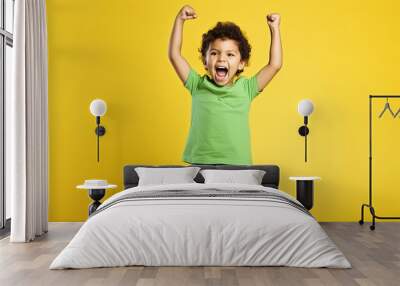 Full body little small fun happy boy 6-7 years old wearing green t-shirt do winner gesture clench fist isolated on plain yellow background studio portrait. Mother's Day love family lifestyle concept Wall mural