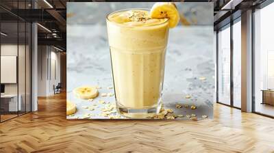 Healthy banana smoothie with oats in a tall glass, garnished with a banana slice and oats Wall mural