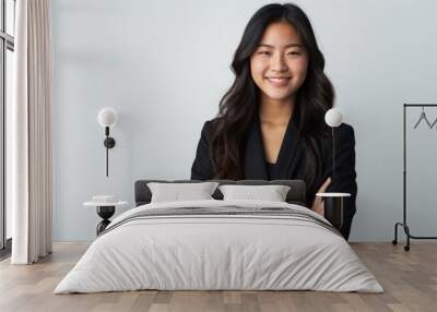 Portrait of a smiling asian businesswoman standing with arms folded and looking at camera isolated over white background Wall mural