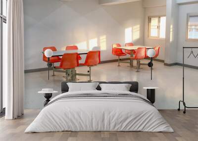 2 tables with 4 orange chairs each in warm light at meeting point in a building Wall mural