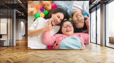 Happy Asian family laying on carpet in living room and smile with their daughter down syndrome child , a lot color balls and teddy bear dolls around them , Activity happy family lifestyle concept. Wall mural