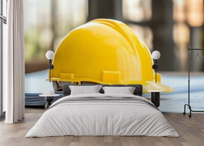 Detailed view of a yellow safety helmet placed atop a stack of construction drawings. Wall mural