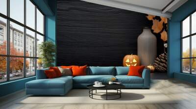 Halloween decor featuring a pumpkin, vase, and autumn leaves on a dark background. Wall mural