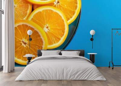 A vibrant blue background with a plate of fresh orange slices, showcasing a colorful and healthy fruit arrangement. Wall mural