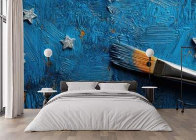 Artistic paintbrush beside silver stars on a vibrant blue textured background. Wall mural