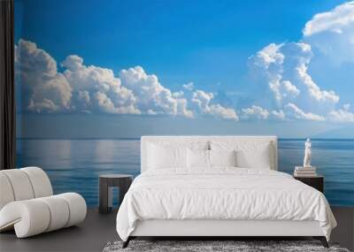 Scenic view of a calm ocean with reflections of clouds in the clear blue sky, offering a serene and tranquil seascape atmosphere. Wall mural