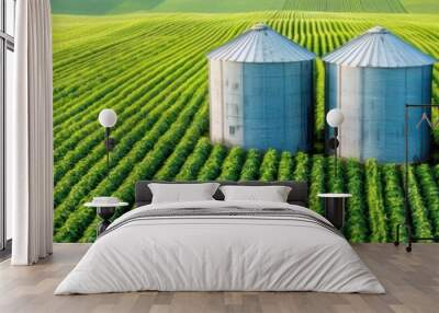 Vibrant green field featuring three silver silos, symbolizing agriculture and rural life in a sunny landscape. Wall mural