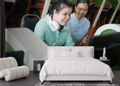 Asian young blind person woman with headphone using computer with braille display assistive device discussing with senior colleague woman in workplace. Wall mural