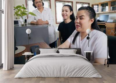 Wide angle view of happy Asian women co-workers in office workplace including person with blindness disability using computer with refreshable braille display assistive device. Disability inclusion. Wall mural