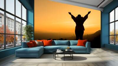 woman raising her arms and enjoying the beautiful sunset Wall mural