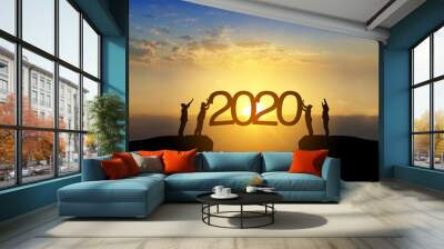 Silhouette image of happy teamwork standing on opposite sides of cliff use their hand push 2020 text to the sky like as set up year 2020 target. Wall mural