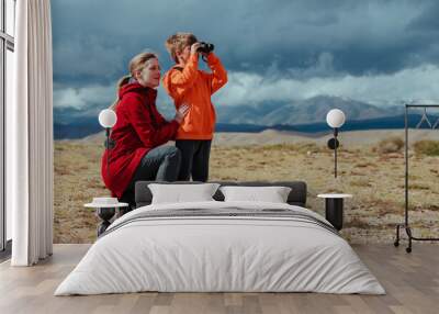 Boy tourist with binoculars and his mother in mountains Wall mural