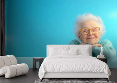 Elderly woman smiles warmly against a bright blue backdrop Wall mural