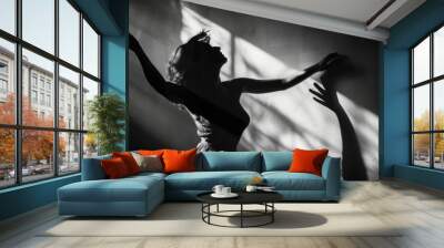 A graceful dancer radiates pure joy as she raises her arms to the beat of the music, casting a mesmerizing shadow in her elegant dress at a concert Wall mural