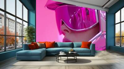 A stylish girl sporting a magenta helmet and matching goggles gazes confidently into the camera, her bold eyewear serving as both a fashion statement and a practical accessory for her adventurous spi Wall mural