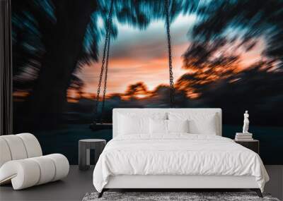 A swing blurs into motion at twilight, surrounded by a vibrant blur of evening sky colors, capturing the essence of nostalgia and carefree childhood moments. Wall mural