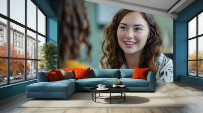 A young woman with curly hair and a bright expression engaged in a conversation Wall mural