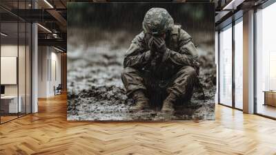 In a muddy battlefield, a soldier covers his face from the pouring rain. The chaotic weather mirrors his exhaustion and determination in the face of adversity. Wall mural