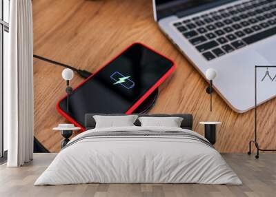 Charging mobile phone battery with wireless device in the table. Smartphone charging on a charging pad. Mobile phone near wireless charger. Wall mural