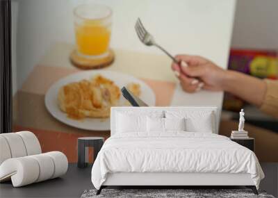 Happy beautiful Asian woman with phone eating fresh salad at table in kitchen and using application texting on smartphone while eating healthy food. Wall mural