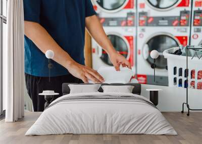 Man doing launder holding basket with dirty laundry of the washing machine in the public store. laundry clothes concept Wall mural