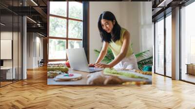 Small business. smiling young entrepreneur Asian Woman. Punch needle craftswoman with laptop computer. in studio workshop. Handmade craft handicraft items Wall mural