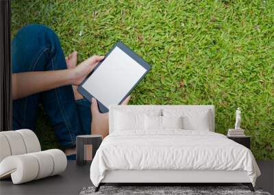 Woman sitting in park on the green grass with laptop, student studying outdoors. Wall mural