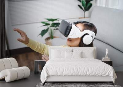 Young Asian woman gamer wearing virtual reality touching air during the VR experience  Future home technology player hobby playful enjoyment concept. Wall mural