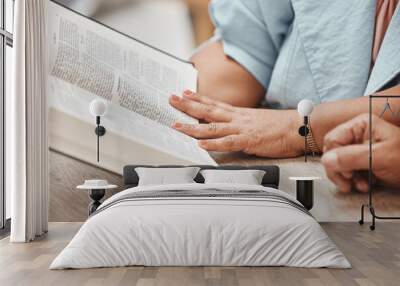 Hands, bible and reading with a senior couple studying a book together in their home during retirement. Jesus, faith or belief with a man and woman praying to god in their house for spiritual bonding Wall mural