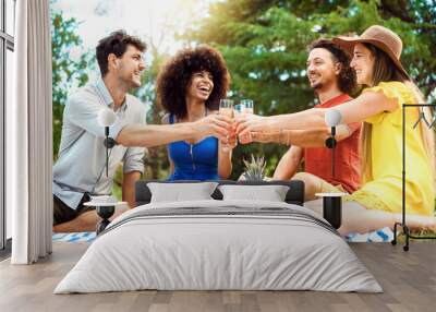 Group of friends having pic-nic in a park on a sunny day - Happy young men and women toasting healthy orange fruit juice at springtime camping - People having fun and relaxing in summer holidays. Wall mural