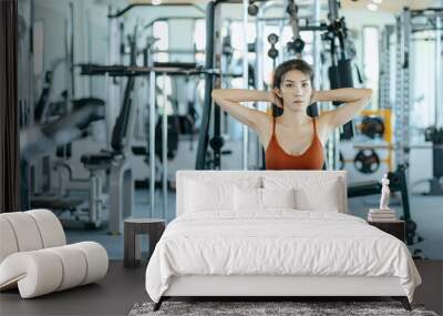 Asian woman in sportswear training sit up at fitness gym. Fitness and workout concept. Wall mural