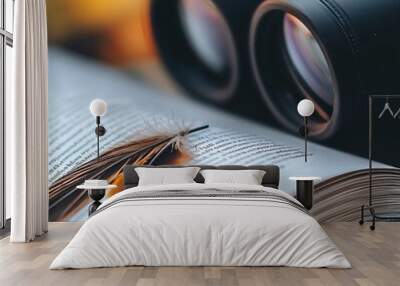 Extreme close-up of a bird guide page with a feather bookmark, binoculars blurred in background Wall mural