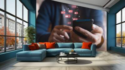 Man hand using a social media marketing concept on mobile phone with notification icons of like, message, comment and star above mobile phone screen. Wall mural